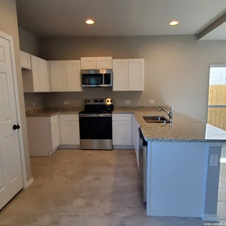 a kitchen with stainless steel appliances a sink a stove a microwave a refrigerator a sink and cabinets