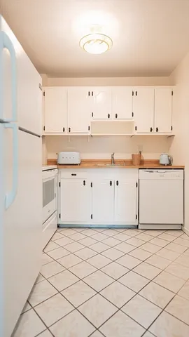 a kitchen with granite countertop white cabinets and white appliances