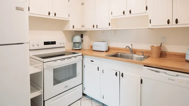 a kitchen with granite countertop white cabinets and white appliances