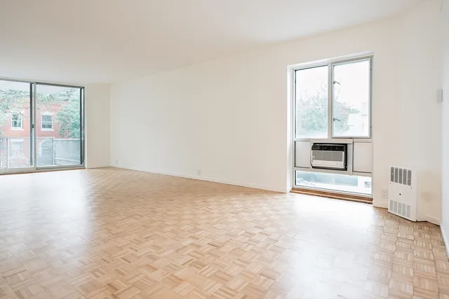 an empty room with windows and fireplace