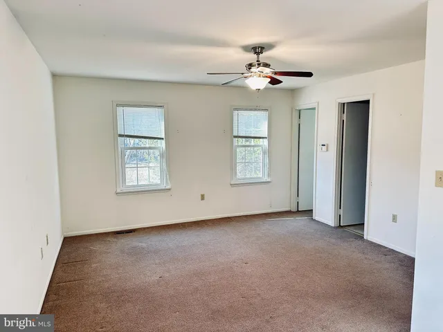 an empty room with windows and fan