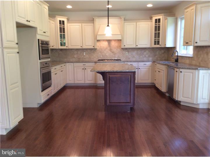 117 North Hillcrest Road Springfield, PA 19064 - Photo 2 of 17 a kitchen with granite countertop wooden floors white cabinets and stainless steel appliances