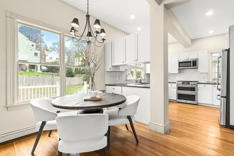 a kitchen with stainless steel appliances a dining table chairs and wooden floor