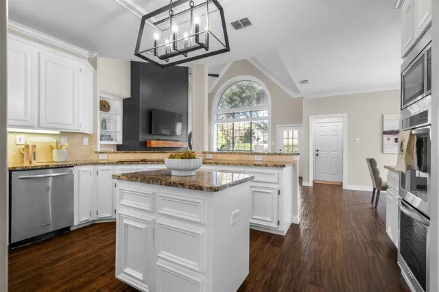 a kitchen with stainless steel appliances granite countertop a stove cabinets and wooden floor