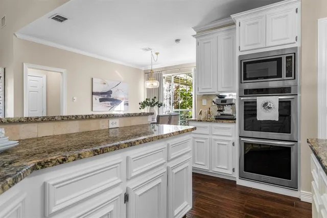 a kitchen with granite countertop white cabinets stainless steel appliances and a counter space