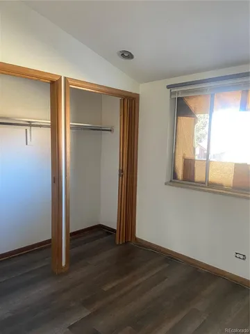 an empty room with wooden floor closet and windows