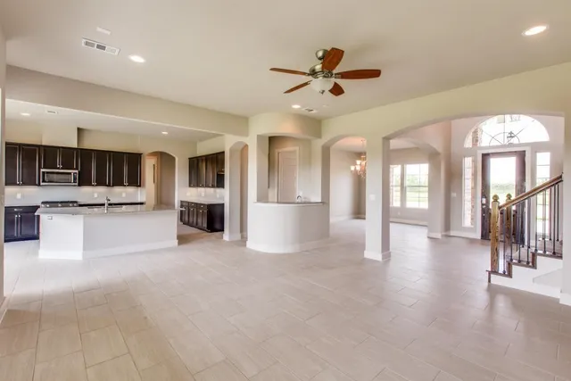 a view of a living room a kitchen and a chandelier fan