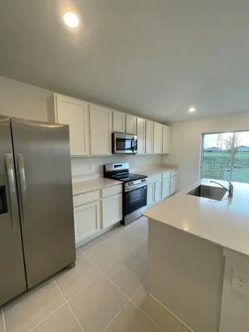 a kitchen with stainless steel appliances granite countertop a refrigerator sink and stove