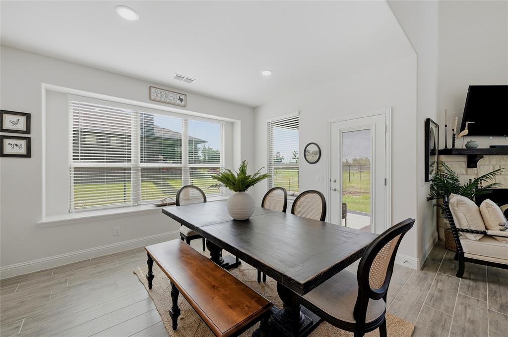 864 Shadow Valley Road Whitesboro, TX 76273 - Photo 13 of 40 Open-concept dining area featuring wood-finish flooring, a large window with horizontal blinds, and a glass-paneled exterior door