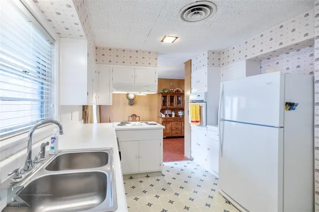 a kitchen with a refrigerator sink and white cabinets