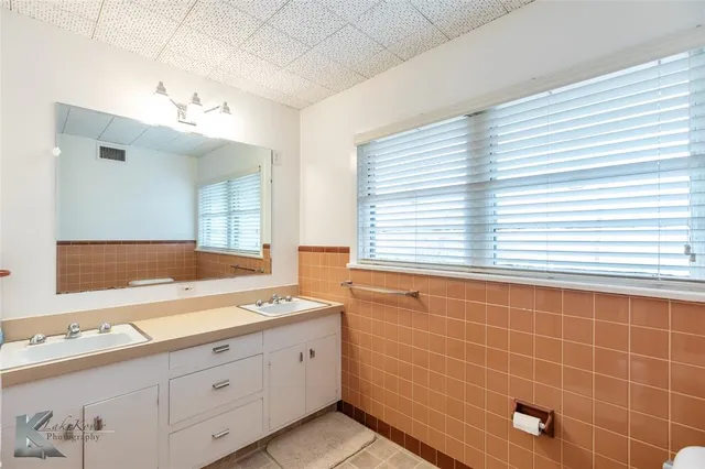 a bathroom with a sink a large mirror and a bathtub next to a window