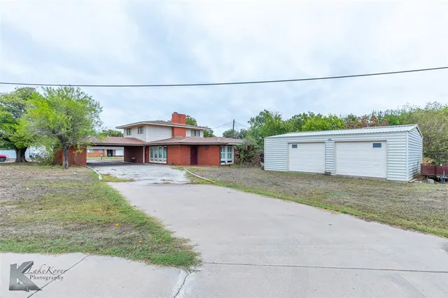 a view of a house with a yard and a large tree