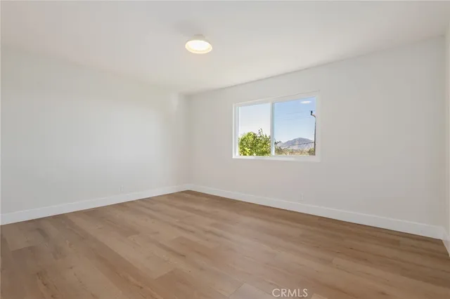 an empty room with a wooden floor and window