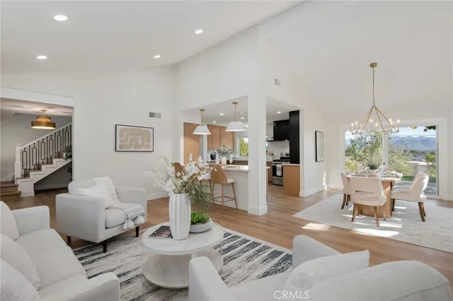 a living room with furniture a chandelier and a dining table with wooden floor