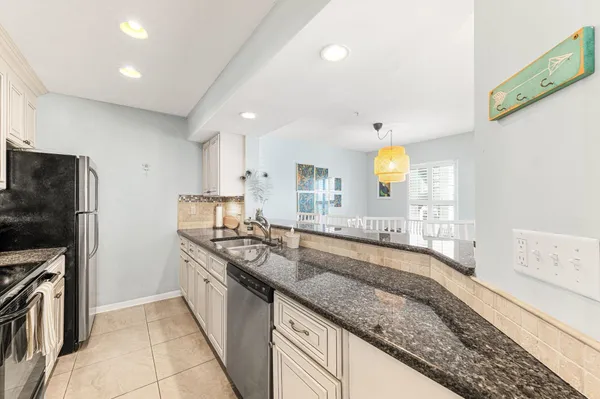 a large kitchen with a large counter top a sink stainless steel appliances and cabinets