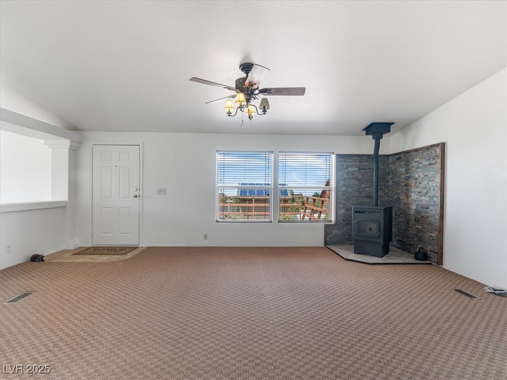 70 West Bonanza Road Las Vegas, NV 89124 - Photo 14 of 71 Unfurnished living room featuring carpet flooring, a wood stove, and a ceiling fan