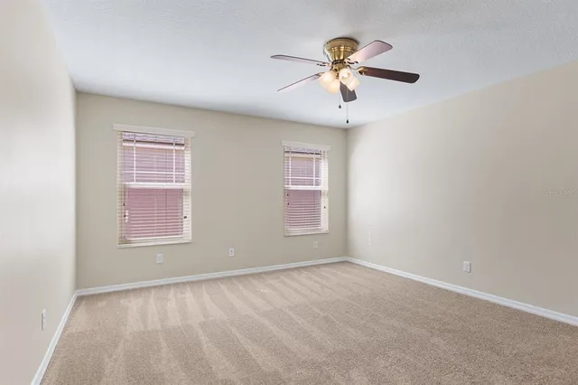 an empty room with windows and fan