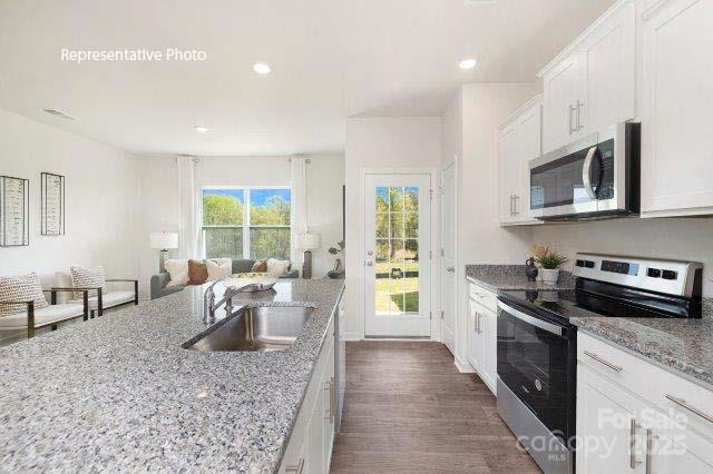 1324 Equestrian Lane York, SC 29745 - Photo 3 of 15 a kitchen with stainless steel appliances granite countertop a stove top oven a sink dishwasher a dining table and chairs with wooden floor