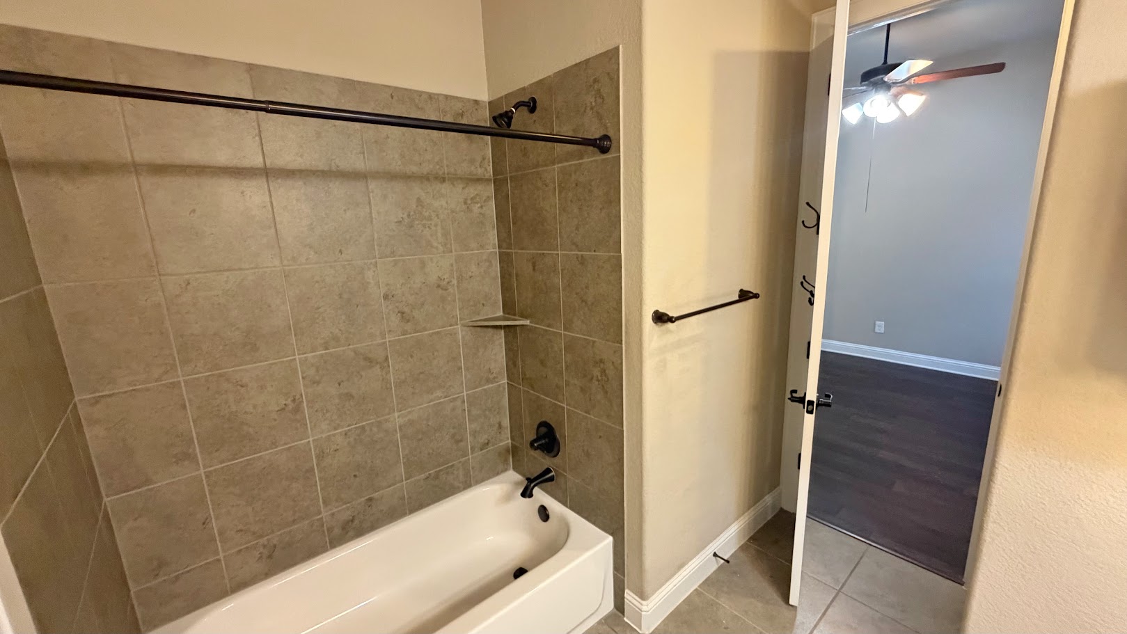 A classic tub and shower combination with a neutral tiled surround provides a functional and well-maintained bathing space.