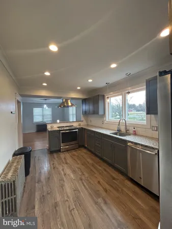 a large kitchen with a large counter top a sink stainless steel appliances and cabinets
