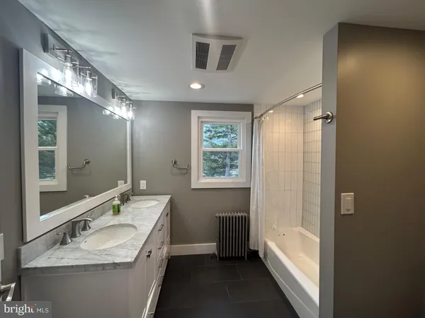 a bathroom with a granite countertop sink a mirror a bathtub and shower