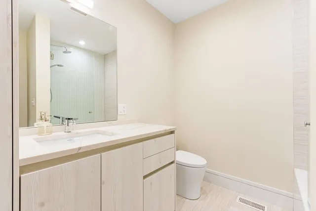 a bathroom with a granite countertop sink a toilet and a mirror