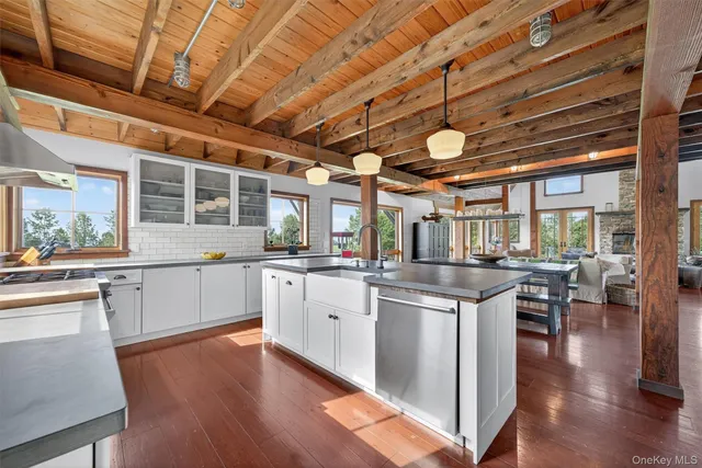 a kitchen with stainless steel appliances granite countertop a stove a sink dishwasher and white cabinets with wooden floor