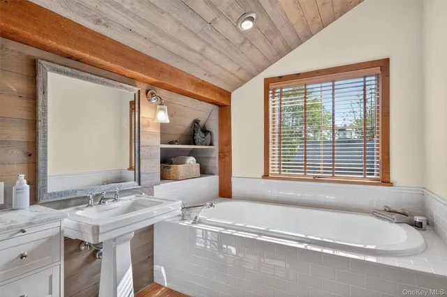 a bathroom with a tub a sink and a mirror