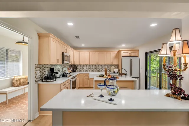 a view of a kitchen with kitchen island a large counter top space a sink a stove and cabinets