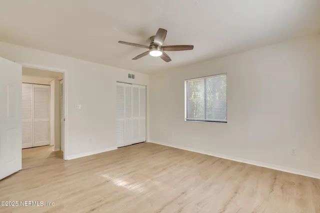a view of empty room with wooden floor and fan