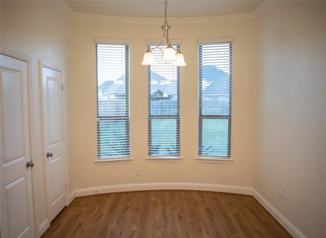 a view of an empty room with wooden floor and windows