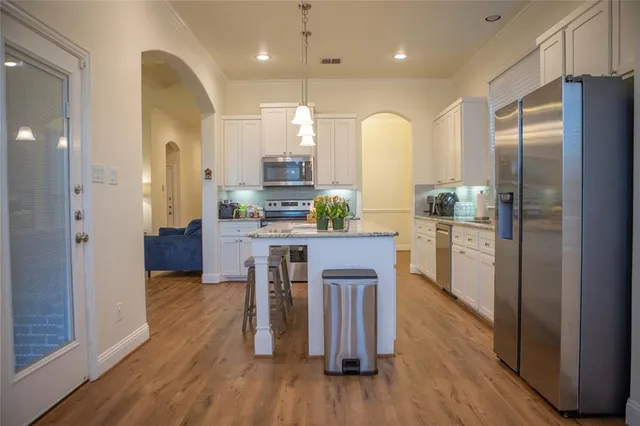 a kitchen with stainless steel appliances a refrigerator a sink dishwasher a stove with wooden floor and cabinets