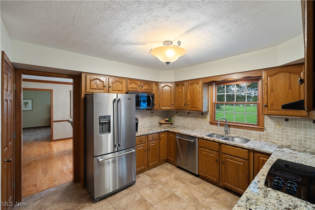 891 Station Road Valley City, OH 44280 - Photo 16 of 45 Kitchen featuring light hardwood / wood-style flooring, sink, light stone countertops, appliances with stainless steel finishes, and a textured ceiling