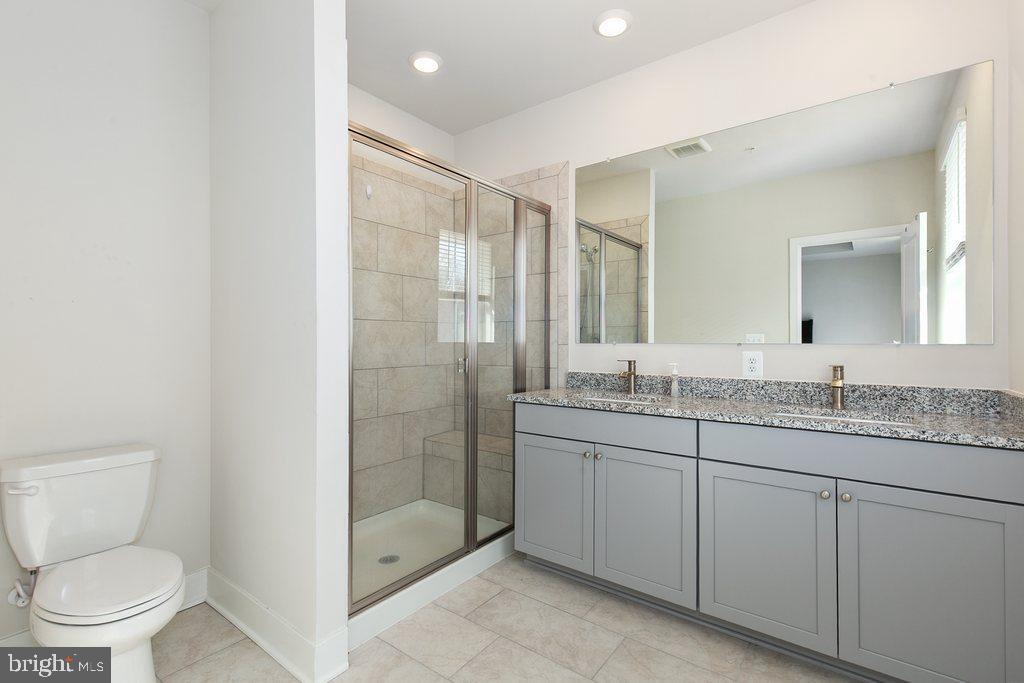 7203 Gringotts Way, Unit A Elkridge, MD 21075 - Photo 12 of 23 a bathroom with a granite countertop sink a toilet and shower