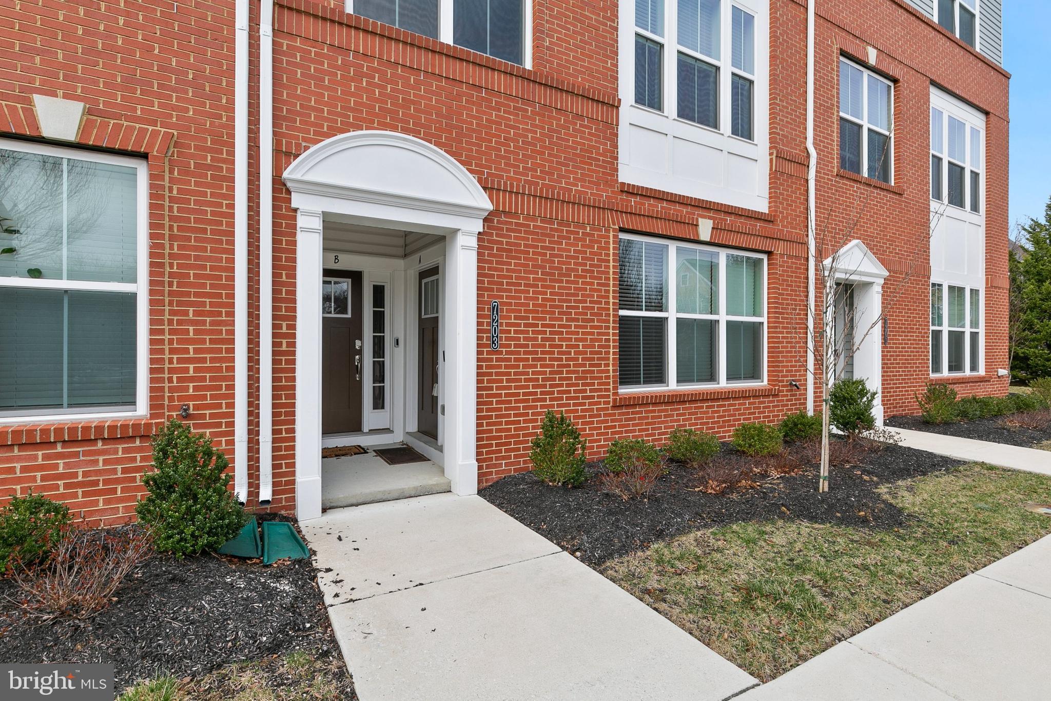 7203 Gringotts Way, Unit A Elkridge, MD 21075 - Photo 2 of 23 a view of a brick house with plants and large tree