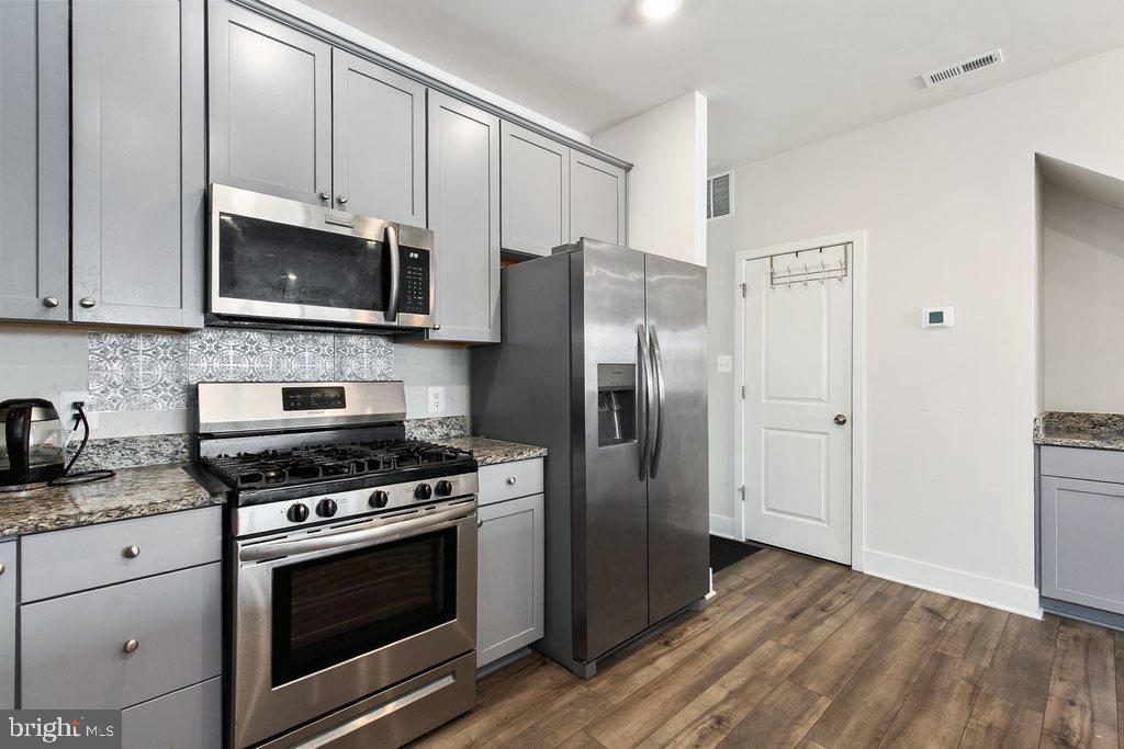 7203 Gringotts Way, Unit A Elkridge, MD 21075 - Photo 7 of 23 a kitchen with granite countertop a refrigerator stove and microwave