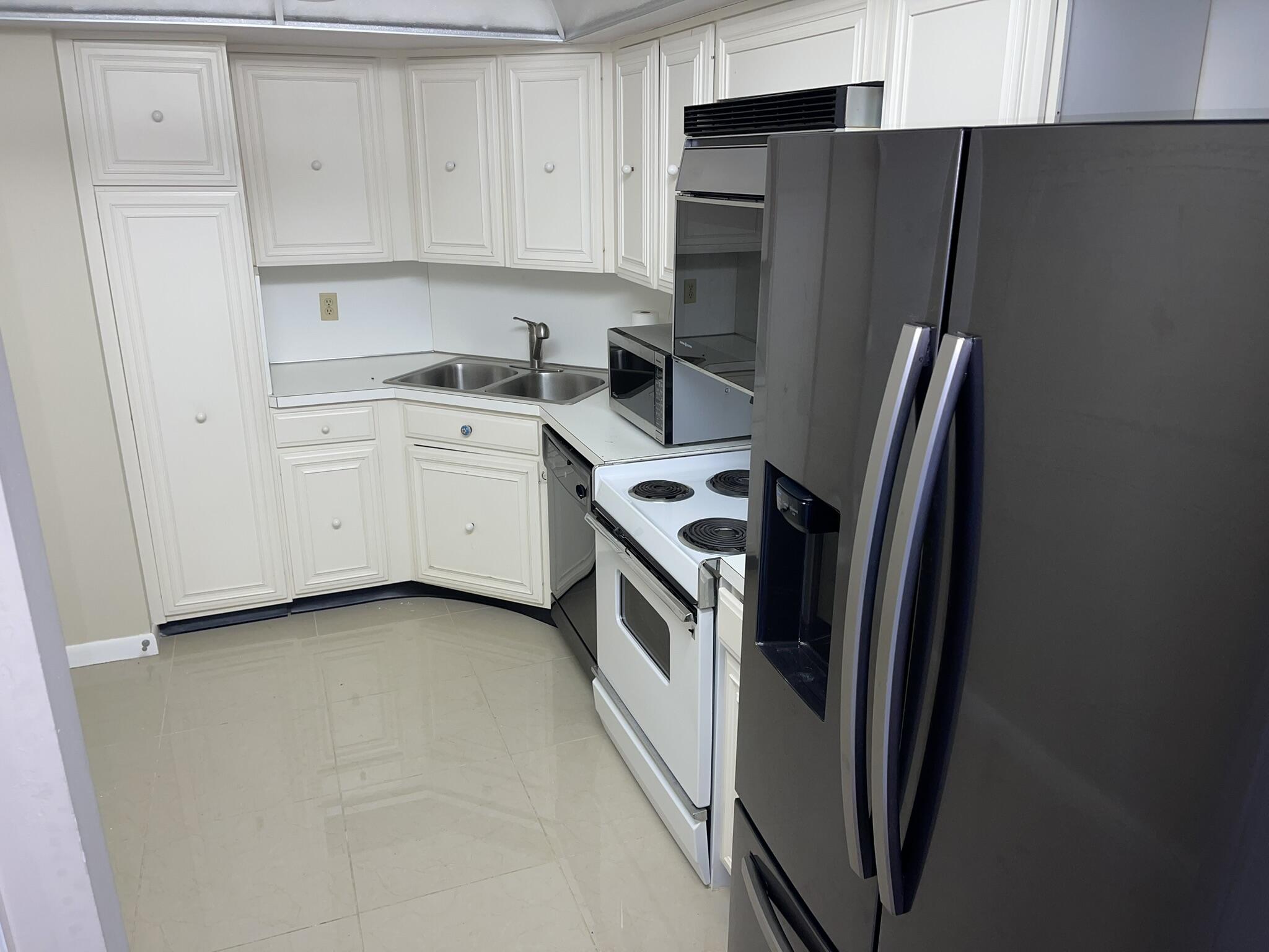a kitchen with a refrigerator sink and white cabinets