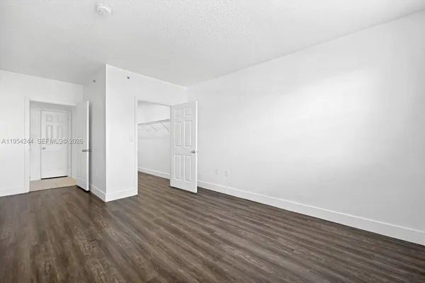 a view of an empty room with wooden floor and closet