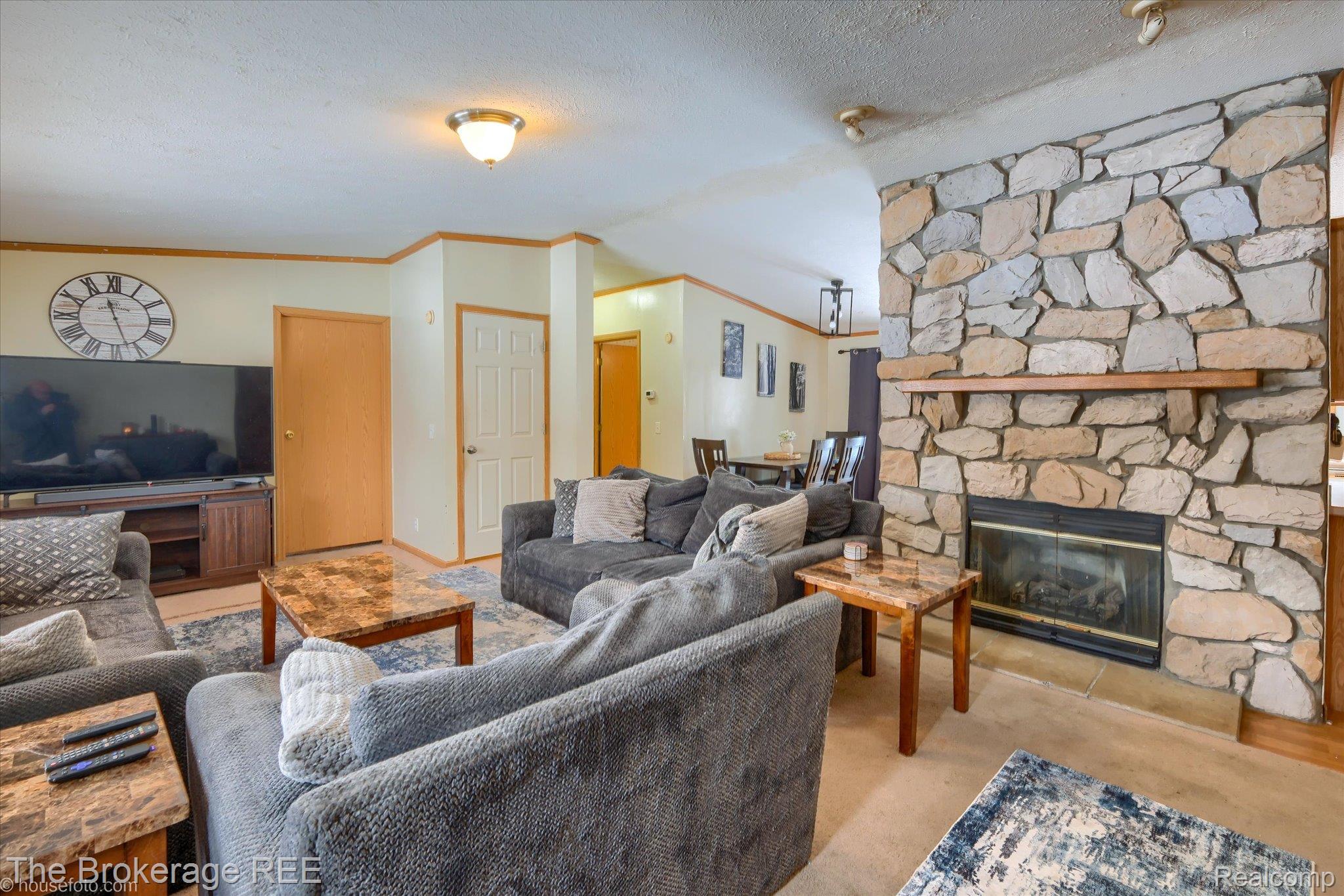 8247 North Center Road Mount Morris, MI 48458 - Photo 12 of 46 Living room with a fireplace, vaulted ceiling, ornamental molding, carpet flooring, and a textured ceiling