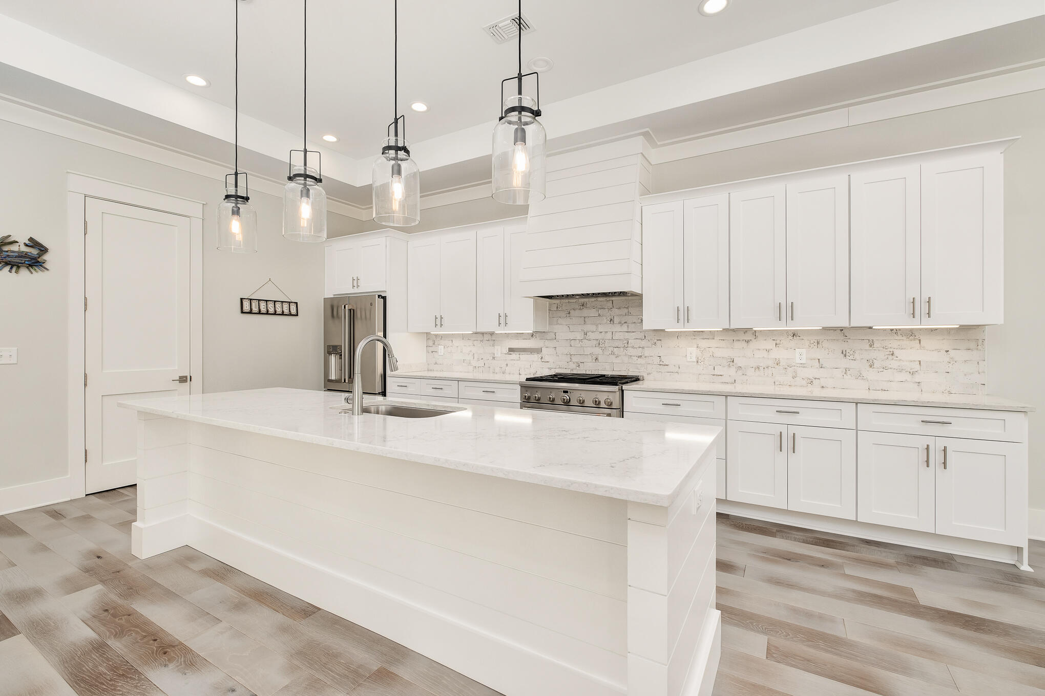 126 Crescent Road Santa Rosa Beach, FL 32459 - Photo 22 of 46 a kitchen with stainless steel appliances granite countertop a sink a stove a refrigerator and white cabinets with wooden floor
