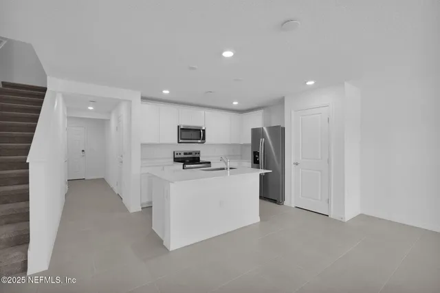 a kitchen with stainless steel appliances kitchen island sink refrigerator and microwave