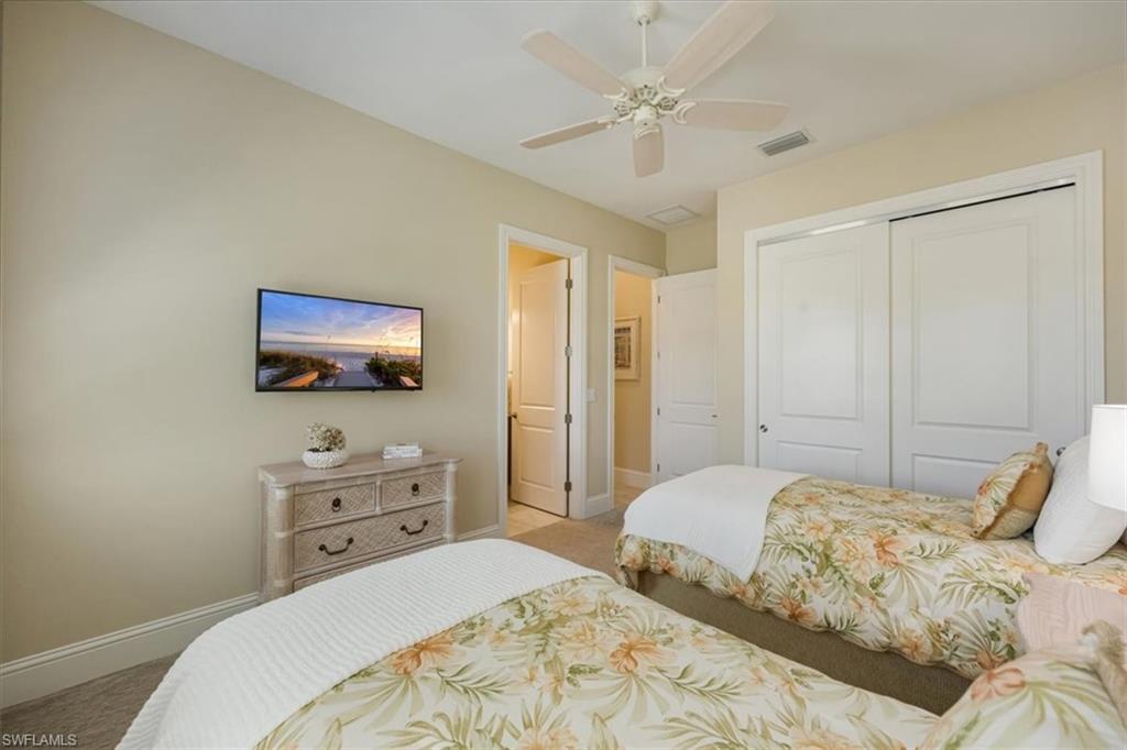 6152 Rodney Bay Lane Naples, FL 34113 - Photo 22 of 45 a bedroom with a bed a window and a flat screen tv