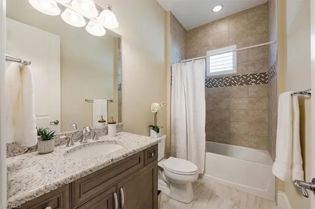 a bathroom with a granite countertop sink a toilet and shower
