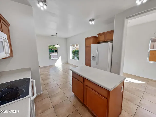 a hall with kitchen island a stove a refrigerator and cabinets