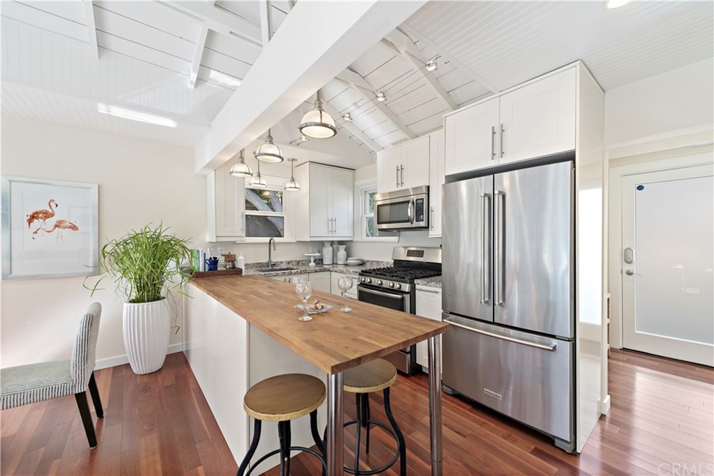 a kitchen with stainless steel appliances a dining table chairs refrigerator and wooden floor