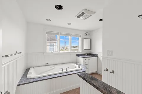 a bathroom with a granite countertop tub sink and mirror