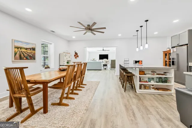 a kitchen with stainless steel appliances a stove a sink a dining table and chairs with wooden floor