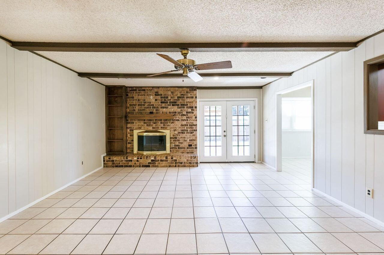 3409 84th Street Lubbock, TX 79423 - Photo 4 of 25 a view of an empty room with a fireplace and a window