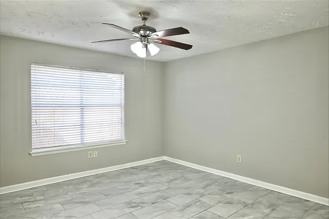 an empty room with a window and a fan