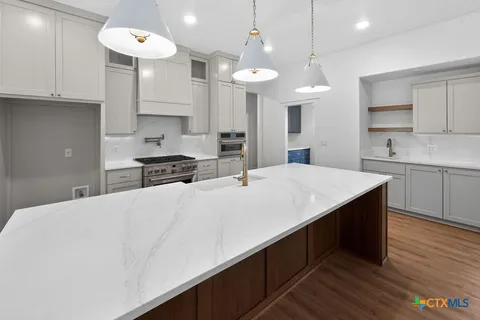 a view of a kitchen with kitchen island white cabinets and wooden floor